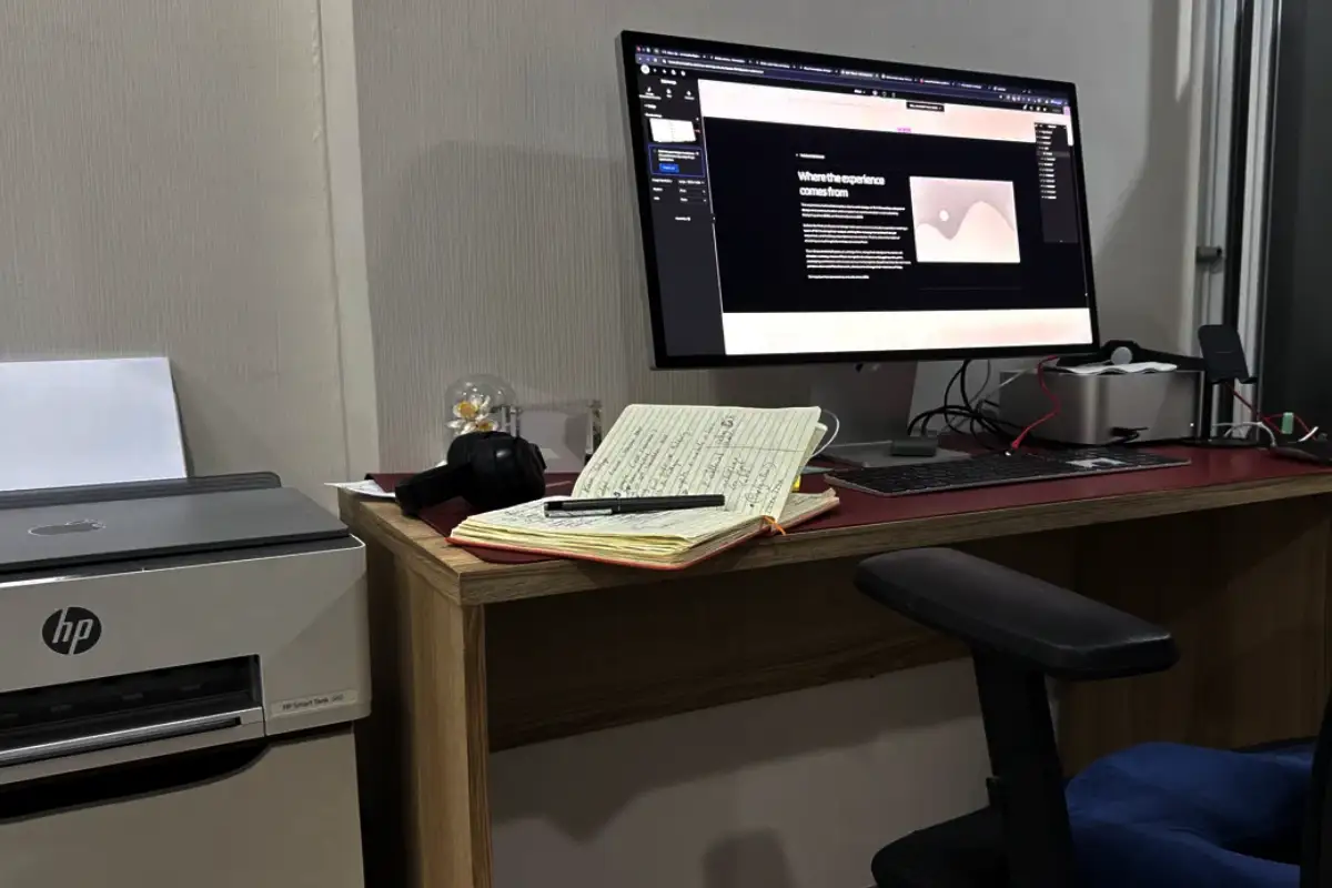 A desk setup showing the Concepduo website being edited, with a handwritten notebook, headphones, and a keyboard, reflecting the studio's remote, one-person way of working.