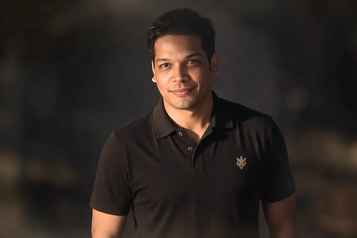 Professional portrait of a web designer wearing a black polo shirt against a dark background
