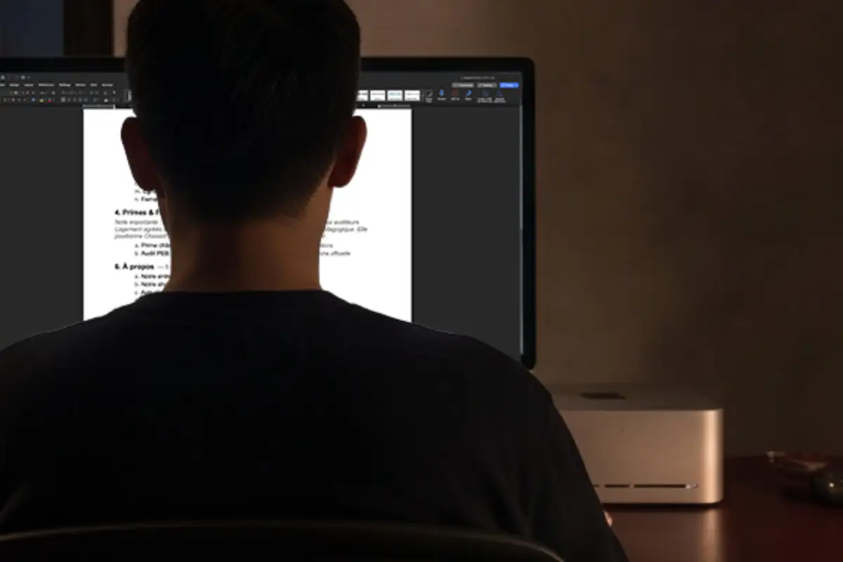 Web designer reviewing website content and project documents on a desktop computer at night